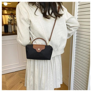 Detailed view of black nylon mini crossbody bag with brown leather handles and strap