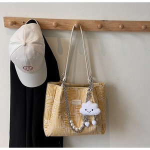 Detail of yellow canvas tote with abstract lines, pearl chain and cloud plush charm