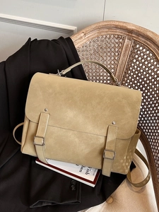 Retro khaki large capacity backpack placed on a vintage chair with classic buckle straps
