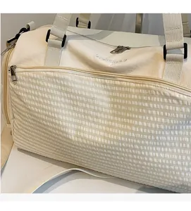 Detail der cremeweißen Reisetasche mit Waffelstruktur-Tasche und verstellbarem Schultergurt