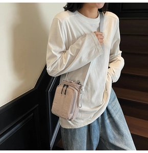 Detail of light purple drawstring nylon crossbody bag with black zipper on the model