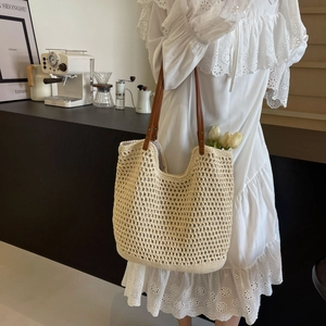 Detail of beige crochet tote bag with brown leather handles and interior flower decor