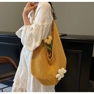 Dettaglio di borsa hobo intrecciata gialla con margherita bianca su un abito bianco chic