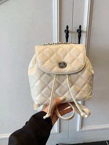 Chic quilted beige mini backpack with chain handle and silver hardware held in hand