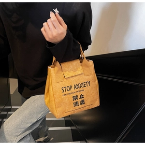 Detail of yellow Tyvek tote bag with Stop Anxiety print and crumpled paper texture