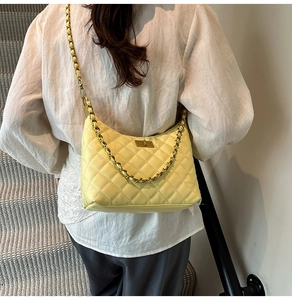 Yellow quilted faux leather hobo bag worn by a model in a minimal indoor setting