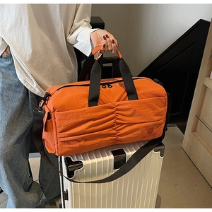 Orange travel bag on white suitcase showing waterproof nylon material and shoulder strap