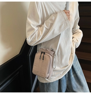 Mini nylon crossbody bag in beige with drawstring closure shown on model during commute