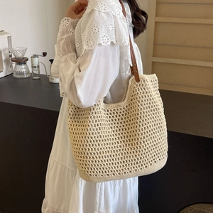 Close-up of beige crochet tote bag featuring brown leather handles with metal rivets