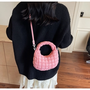 Sac à bandoulière rose matelassé porté, montrant la taille et les détails de la poignée