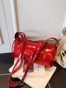 Glossy red cylinder bag with thin adjustable straps on minimalist white background