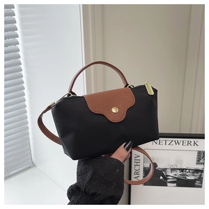 Detail of mini black nylon tote bag featuring brown leather flap and gold snap button
