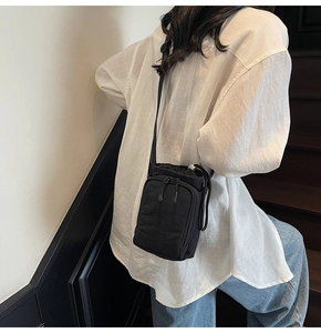 Back view of a compact black nylon crossbody bag showing adjustable strap and daily use look