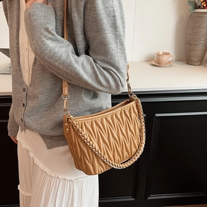 Sac seau plissé kaki porté à l'épaule avec une élégante bandoulière en chaîne