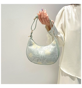 Close-up of light green hobo bag with floral patterns and gold hardware detail