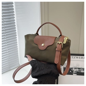 Detail of army green nylon mini bag with leather handles and gold metal hardware