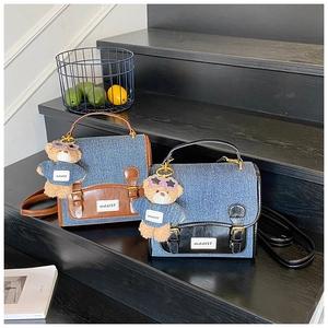 Detail of denim and PU leather crossbody bags with bear charms on black steps