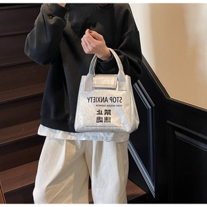 Silver DuPont paper tote bag with STOP ANXIETY print shown on model at a staircase