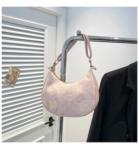 Detail of floral print on a lavender half-moon bag with adjustable leather strap and hardware