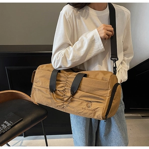 Detailed view of khaki travel bag showing unique pleated texture and adjustable shoulder strap