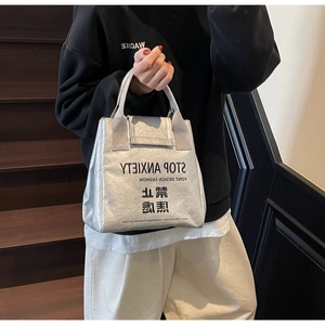 Detail of silver metallic Tyvek tote bag featuring bold Stop Anxiety text on stairs