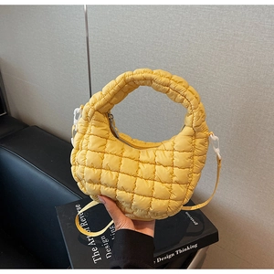 Gros plan d'un sac nuage matelassé jaune avec coutures à carreaux et fermeture éclair