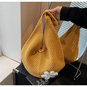 Dettaglio della borsa tote gialla intrecciata con trama a rete e decoro a forma di margherita