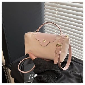 Detail of light pink nylon handbag showing leather flap and golden metal clasp