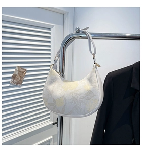 Detail of white hobo bag with yellow floral jacquard and golden metal buckle hardware