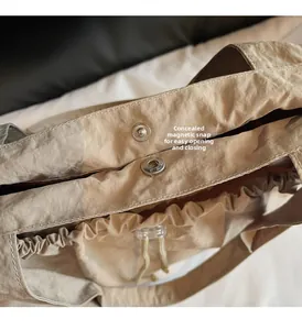 Detail der unsichtbaren Magnetschnalle und Kordelzug am beige Nylonschultertasche