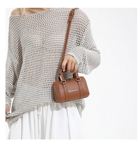 Brown lychee leather mini barrel bag shown on model featuring silver hardware and strap