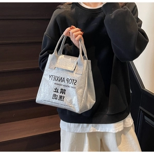 Detailed close-up of metallic silver tote bag with Stop Anxiety slogan and strap detail