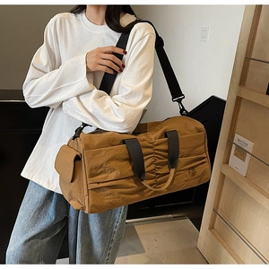 Caramel travel tote with pleated design and detachable strap shown on a model