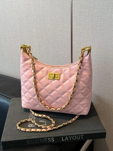 Pink quilted leather bucket bag with gold chain strap displayed on a book prop