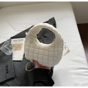 Détail du sac à main matelassé blanc montrant la texture rembourrée sur une veste grise