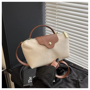 Detail of minimalist nylon dumpling bag with leather flap and golden button hardware