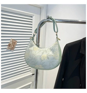 Detail of floral print and texture on a light green crescent-shaped shoulder bag