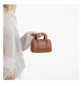 Detail of a brown leather Boston bag with lychee texture and dual zippers