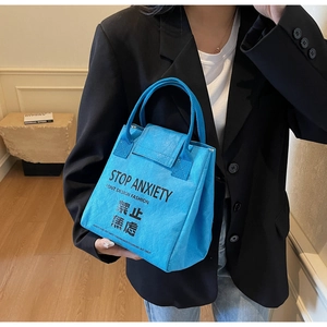 Detail view of sky blue Tyvek tote bag featuring bold Stop Anxiety text print