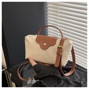 Detailed shot of a beige nylon mini bag with brown leather flap and golden hardware