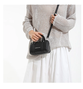 Mini black lychee texture Boston bag with white text and silver hardware worn by a model