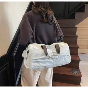 Close-up of stylish ice blue waterproof nylon travel bag with pleated front and shoulder strap