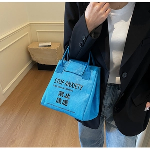 Detail of bright blue Tyvek tote bag featuring bold Stop Anxiety text on person