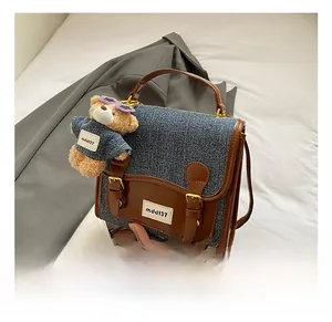 Detailed view of denim and leather patchwork backpack with a teddy bear charm and buckle