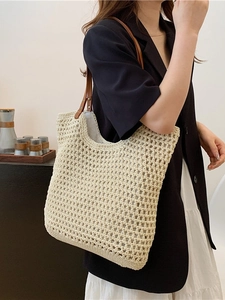 Beige woven tote bag with brown leather handles worn by a model in a casual summer outfit