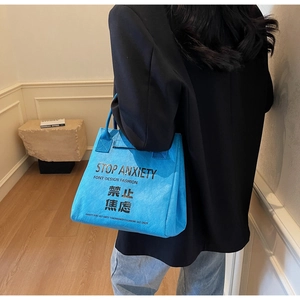 Close-up of bright blue DuPont paper tote bag with black Stop Anxiety slogan print
