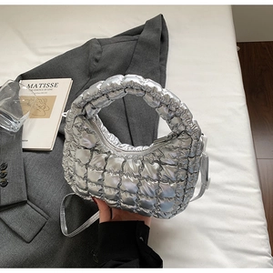 Détail du sac hobo matelassé argenté sur blazer gris avec texture métallique