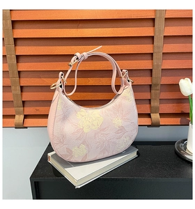 Close-up of pink half-moon bag with floral patterns on a wooden lifestyle background
