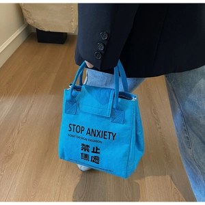 Detail showing bright blue waterproof DuPont paper tote bag with STOP ANXIETY bold print