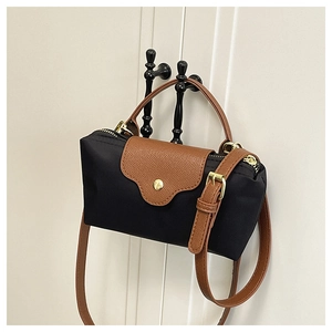 Detail of contrast nylon mini bag with brown leather flap and golden snap closure